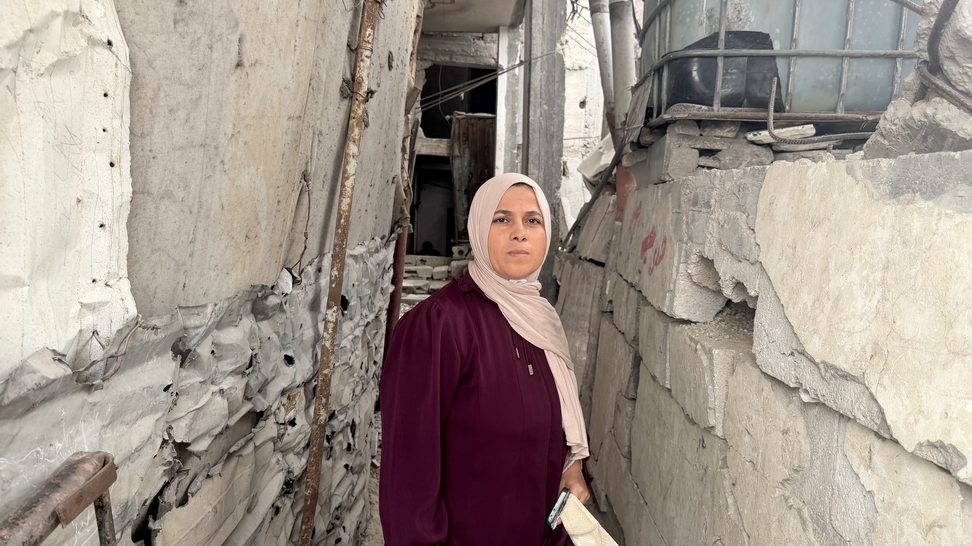 Mahasen Abu Samra in a damaged room of her house