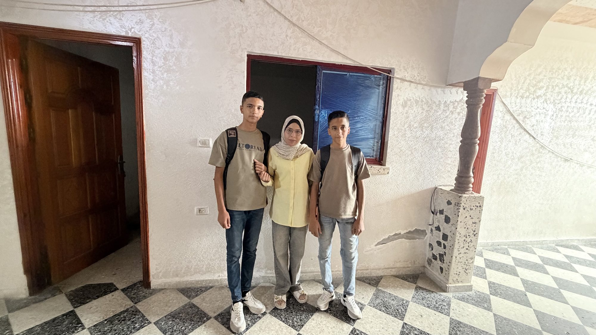Samah Asfour with two of her children in a doorway