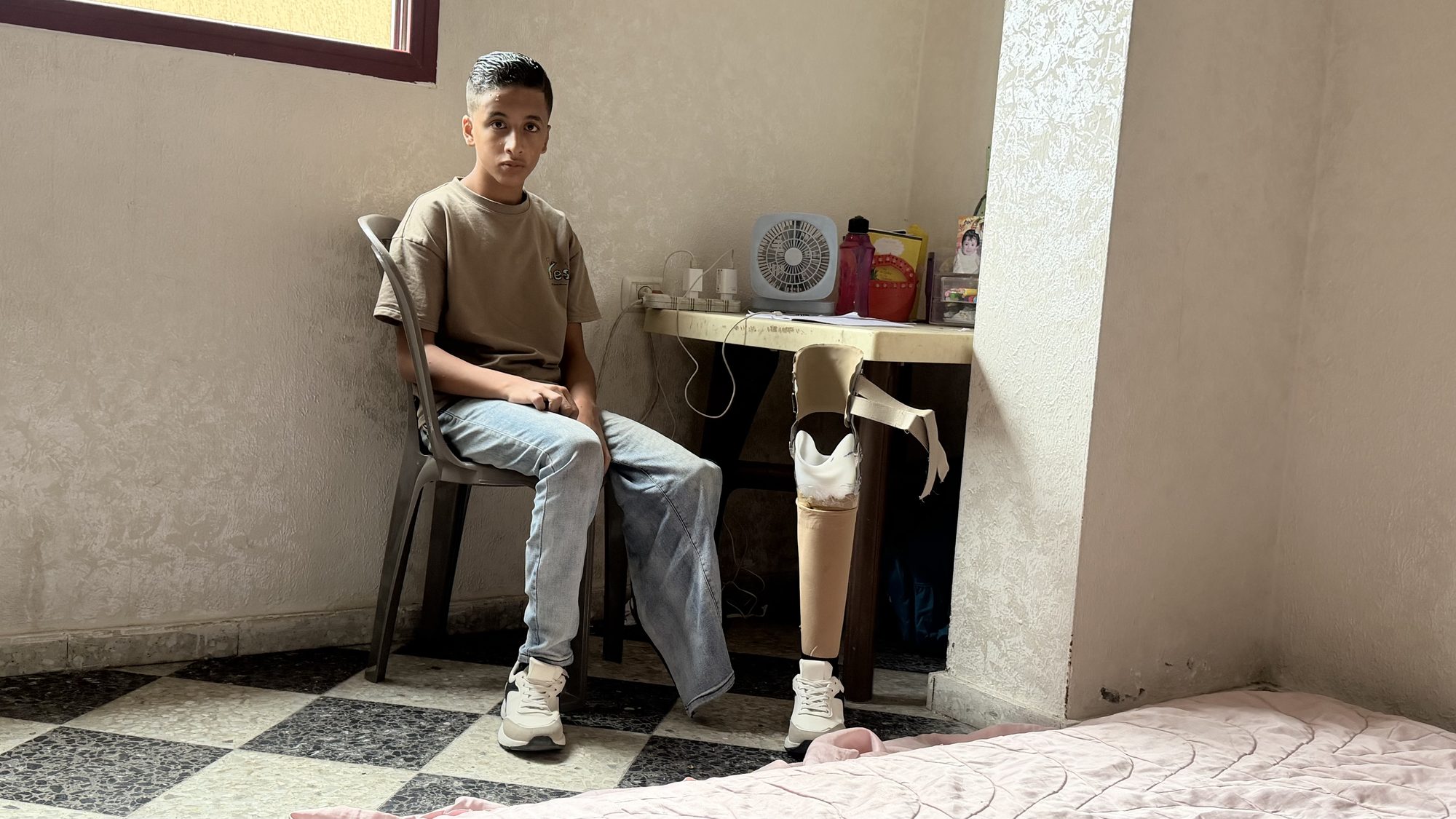 Yamen, Samah’s son, seated at a table with a prosthetic leg