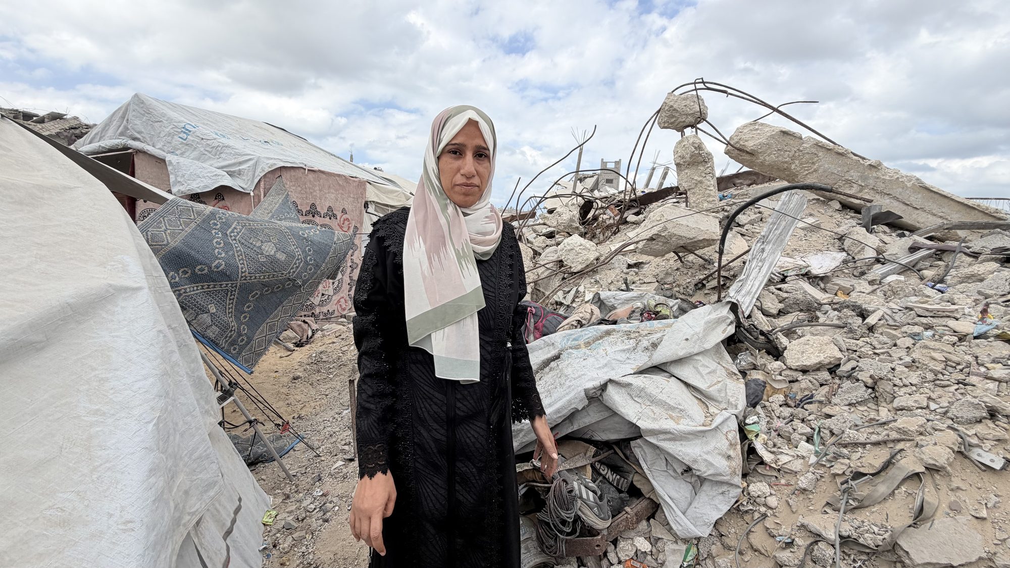 Suhair Abu Nimr standing amid the rubble of destroyed buildings