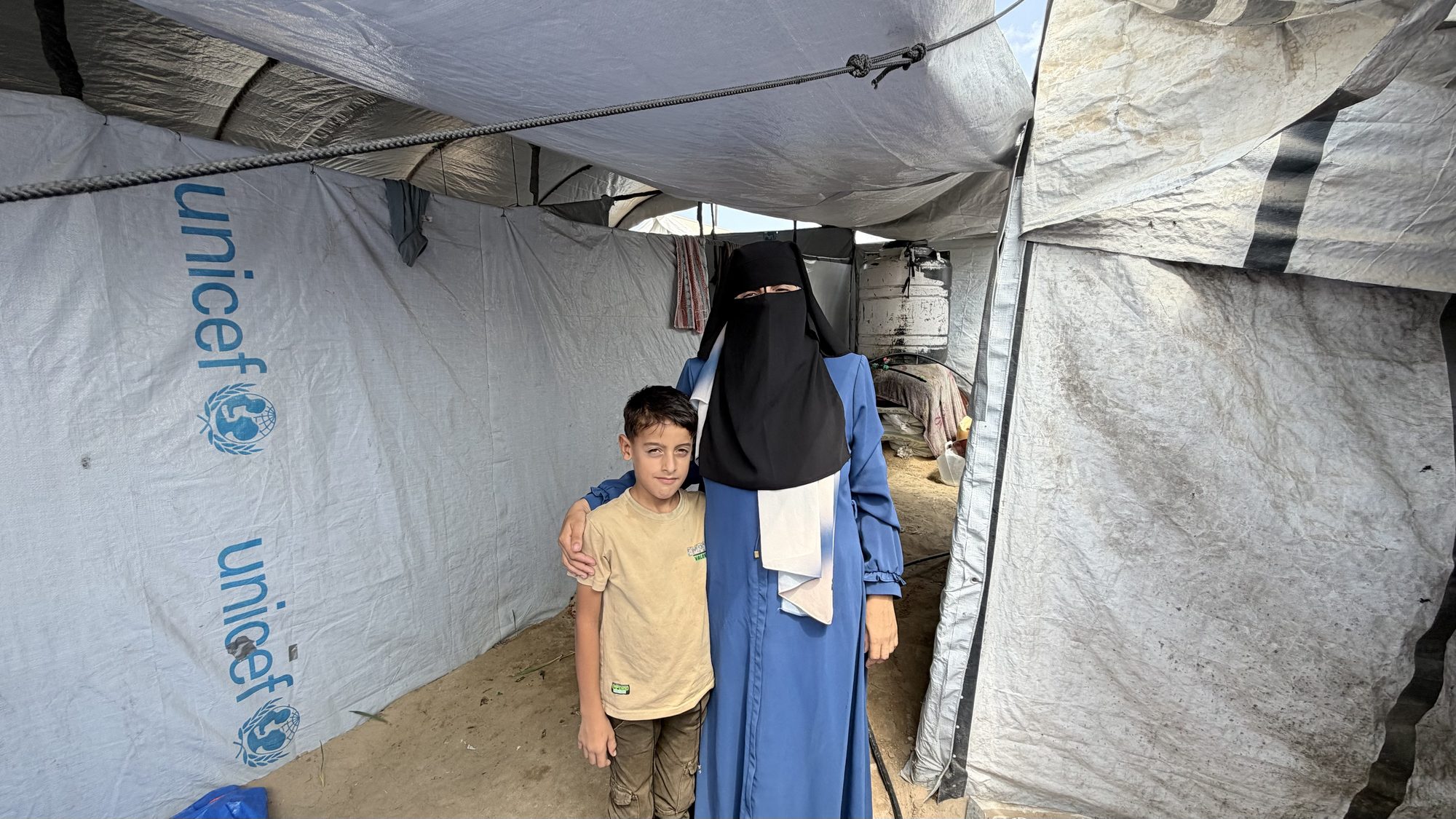 Yasmin al-Sbeihy stands with one of her children in their tent